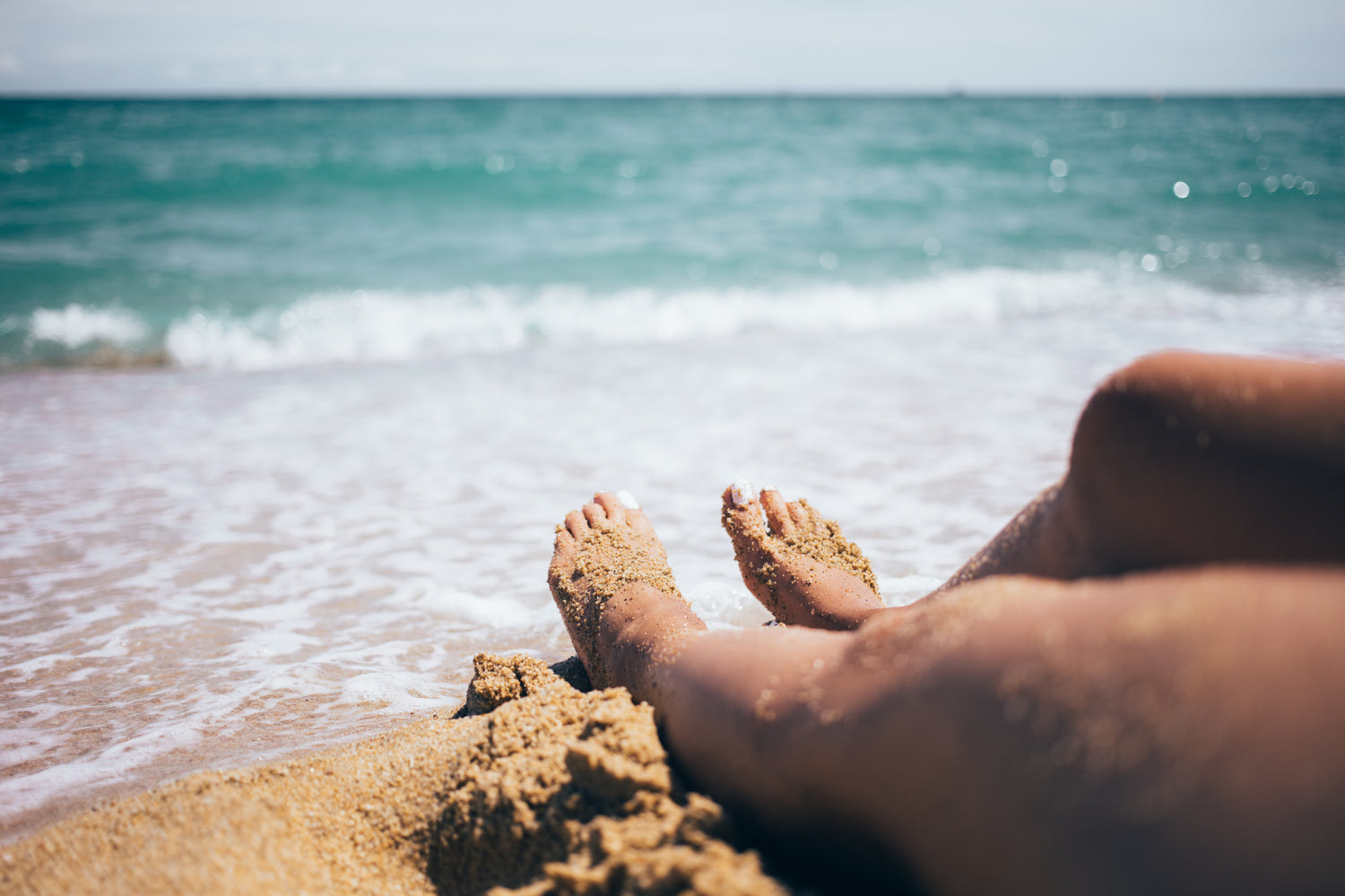 Image of person's feet in the sand near the beach